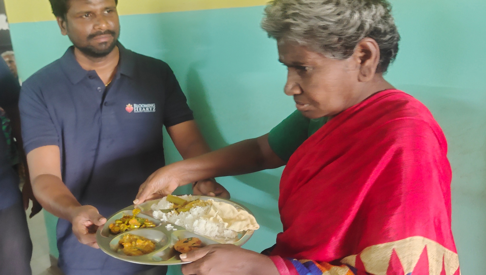 Volunteers serving a warm meal to a rescued elderly person